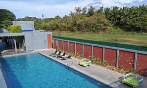 Una piscina amb gandules, una paret de maó i una tanca verda.