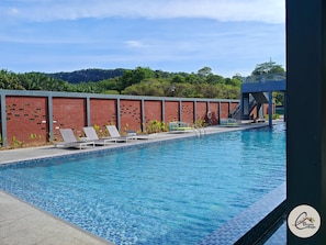 A swimming pool with lounge chairs, a brick wall, and a view of greenery in the background. - Trival Blessing Cottage Homestay @ Sri Indah Sandakan (Sandakan)