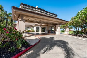 Un hotel con entrada techada, palmeras y cielo despejado.