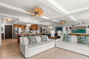 A modern living room with a sofa, a coffee table, and a kitchen in the background. - Luxurious Ocean View Condo Steps to Kaanapali Beach -Whaler 807 (Lahaina)
