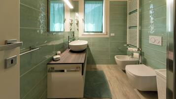 Une salle de bain comprenant un lavabo, des toilettes et un bidet, un miroir et une fenêtre.