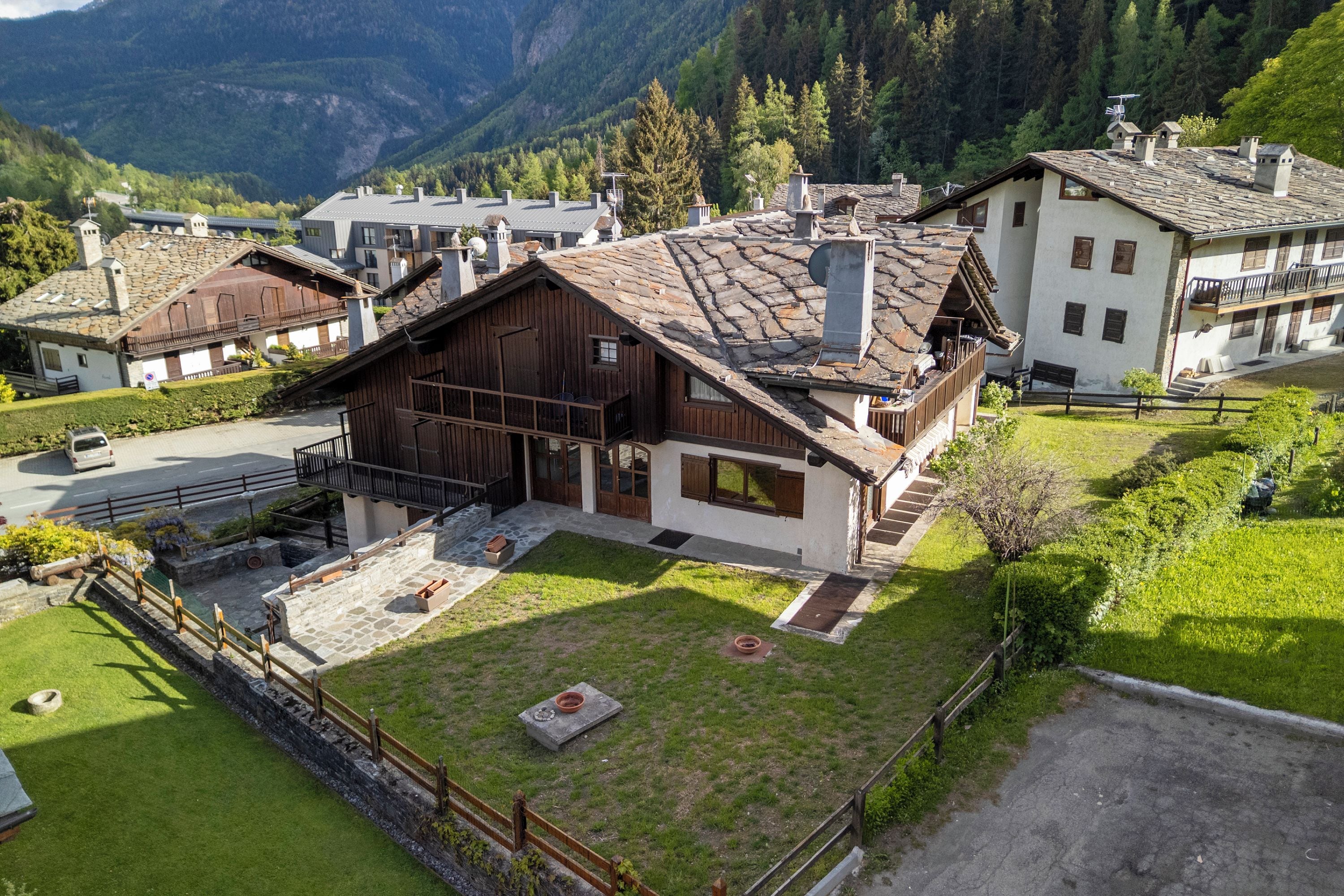 A traditional chalet with a stone facade, wooden balcony, and a stone courtyard.