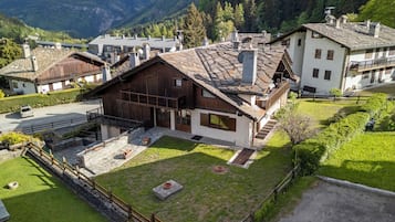 A traditional chalet with a stone facade, wooden balcony, and a stone courtyard.