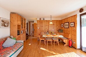 Interior de madeira com sofá, mesa de jantar, cadeiras e extintor de incêndio.