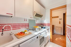 Una cocina moderna con gabinetes blancos, estufa de acero inoxidable y salpicadero a cuadros rojo y blanco.