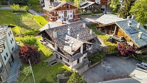A residential area with multiple houses, including a large wooden house with a balcony and a smaller house with a stone facade. - Family Apartment Steps From Ski Lifts (Courmayeur)