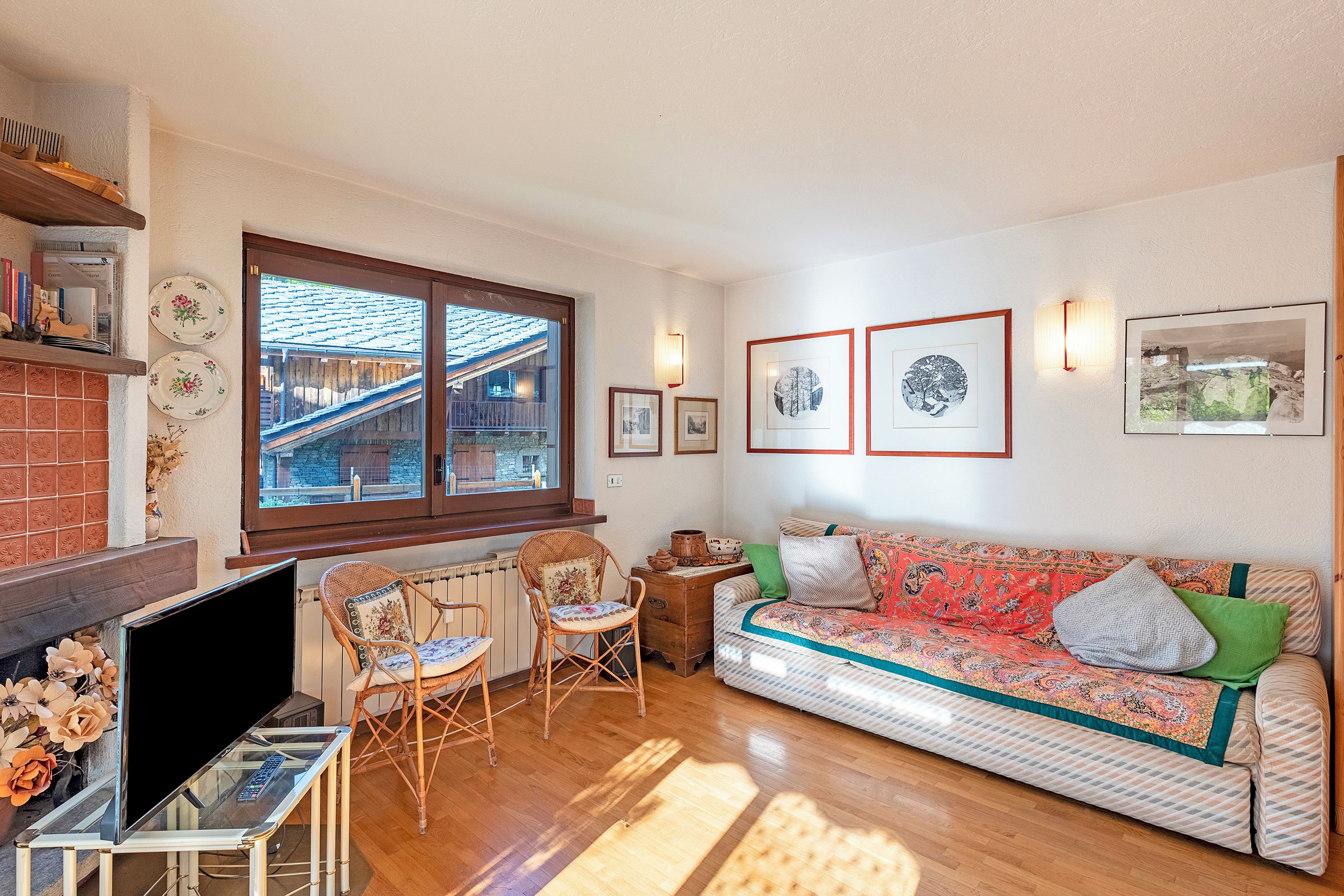 A living room with a sofa, chairs, a TV, a fireplace, and a window with a view of a building.