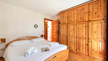 A bedroom with a wooden bed, a wardrobe, and a door leading to another room.