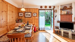 A dining area with wooden walls, a table set with plates, glasses, and a bouquet of flowers. - Family Apartment Steps From Ski Lifts (Courmayeur)