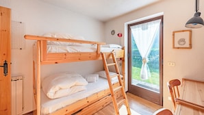 A bunk bed room with a wooden ladder, a desk, and a window with curtains. - Family Apartment Steps From Ski Lifts (Courmayeur)
