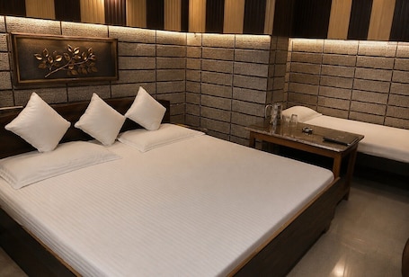 A hotel room with a large bed, a bedside table with a lamp, and a decorative wall panel.. Hotel Kaushalya Residency