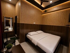 Un dormitorio con cama, escritorio, silla, espejo y ventilador de techo.
