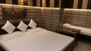 A hotel room with a large bed, a bedside table, and a wall-mounted decorative piece. - Hotel Kaushalya Residency (Berinag)