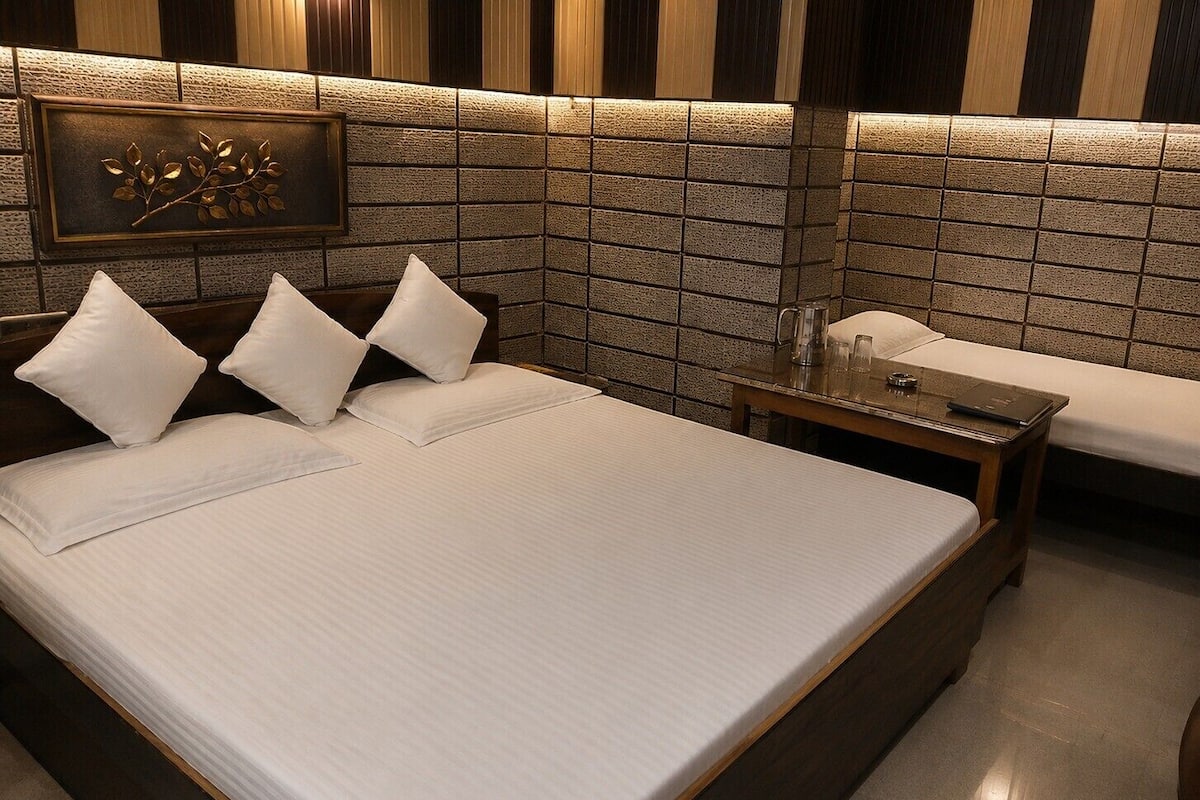 A hotel room with a large bed, a bedside table, and a wall-mounted decorative piece.