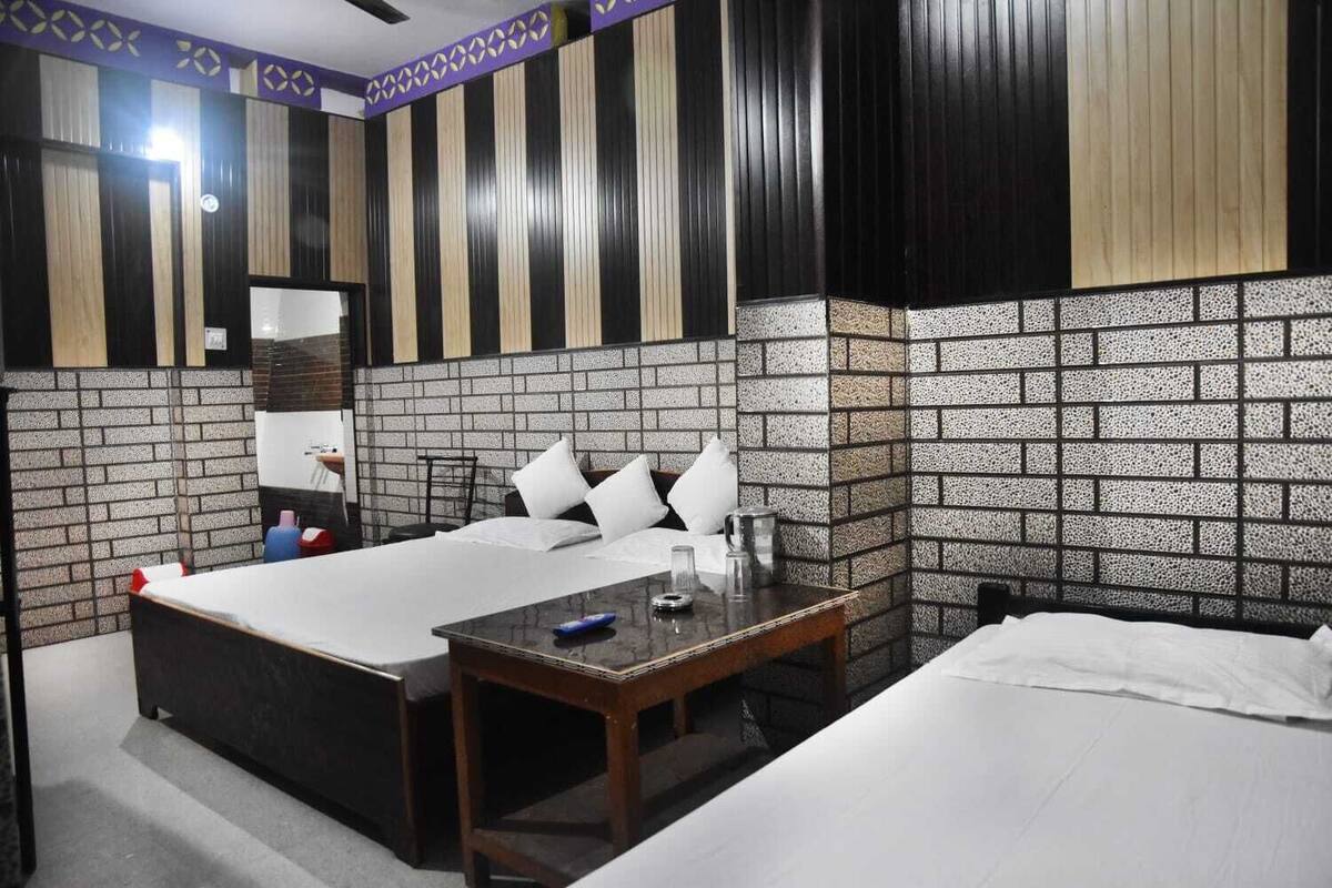 A hotel room with a bed, bedside table, and a small desk.