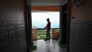 A man standing on a balcony with a view of a green landscape and mountains. - Hotel Kaushalya Residency (Berinag)