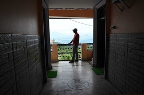 A man standing on a balcony with a view of a green landscape and mountains. - Hotel Kaushalya Residency (Berinag)