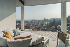A balcony with a city view, a sofa with cushions, and a chair. - Villa Olivo With Garden & Pool (Montano Lucino)