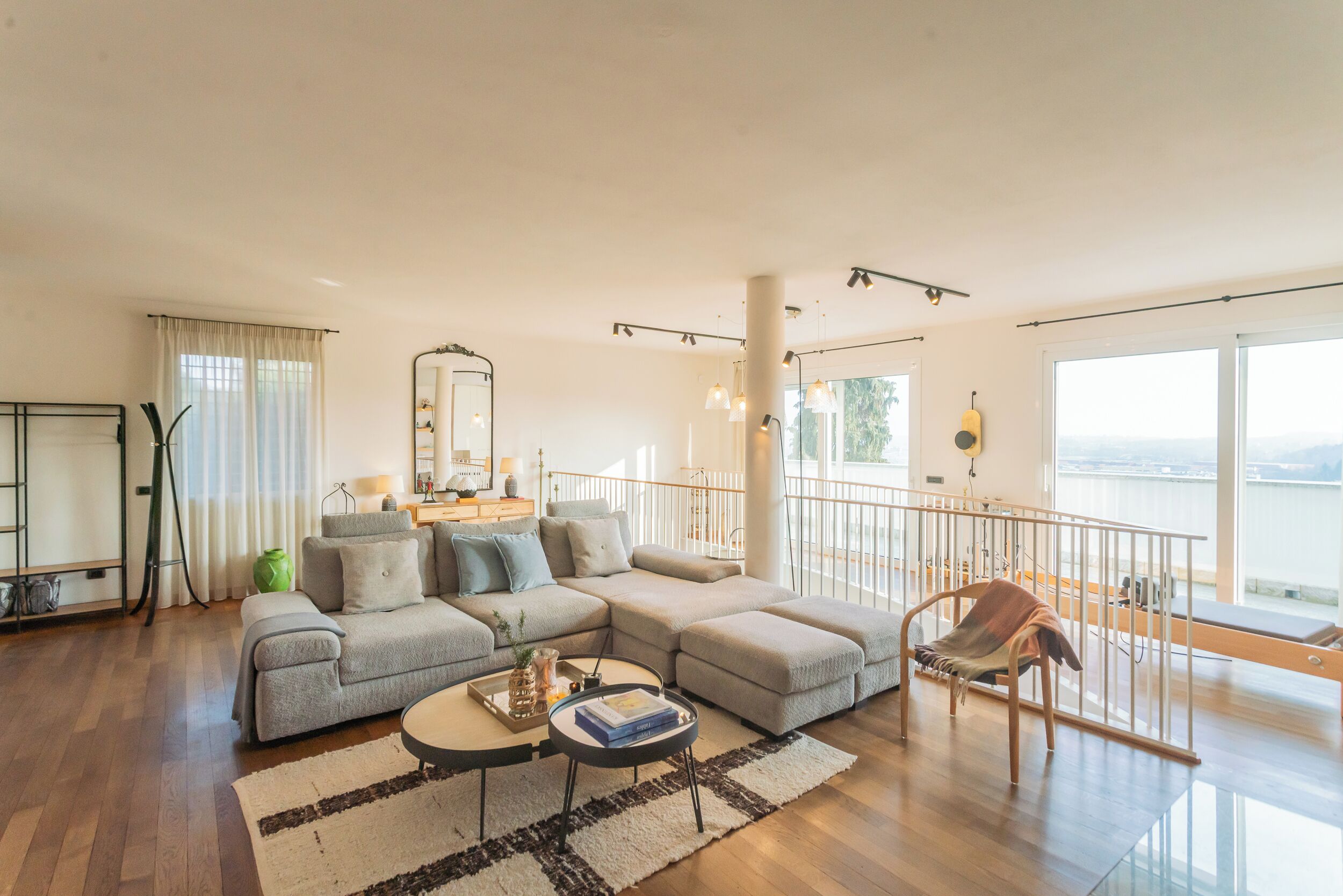 A modern living room with a sectional sofa, a small round coffee table, and a view of the water.