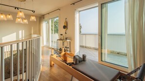 A room with a massage table, exercise equipment, and large windows offering a view.