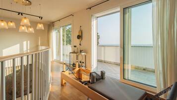 A room with a massage table, exercise equipment, and large windows offering a view.