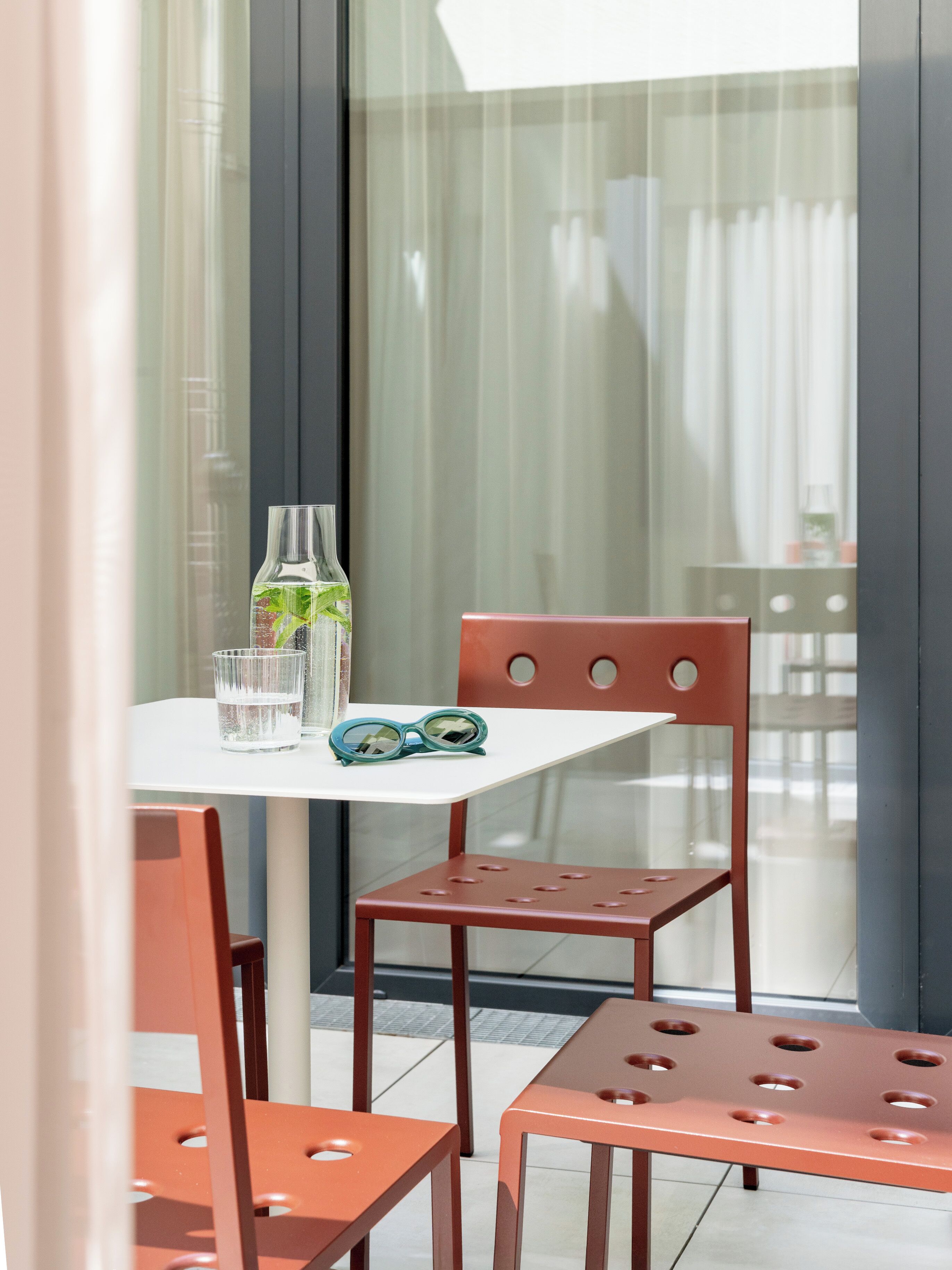 A modern outdoor seating area with a table and chairs, a glass of water, and a bottle of water.
