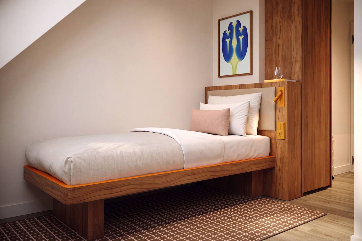 Ein Schlafzimmer im Loft-Stil mit Bett, Holz-Kopfteil und kleinem Fenster.