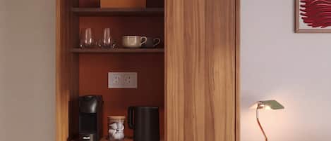 Un meuble en bois doté d’étagères contenant des ustensiles de cuisine, une machine à café et un bocal.