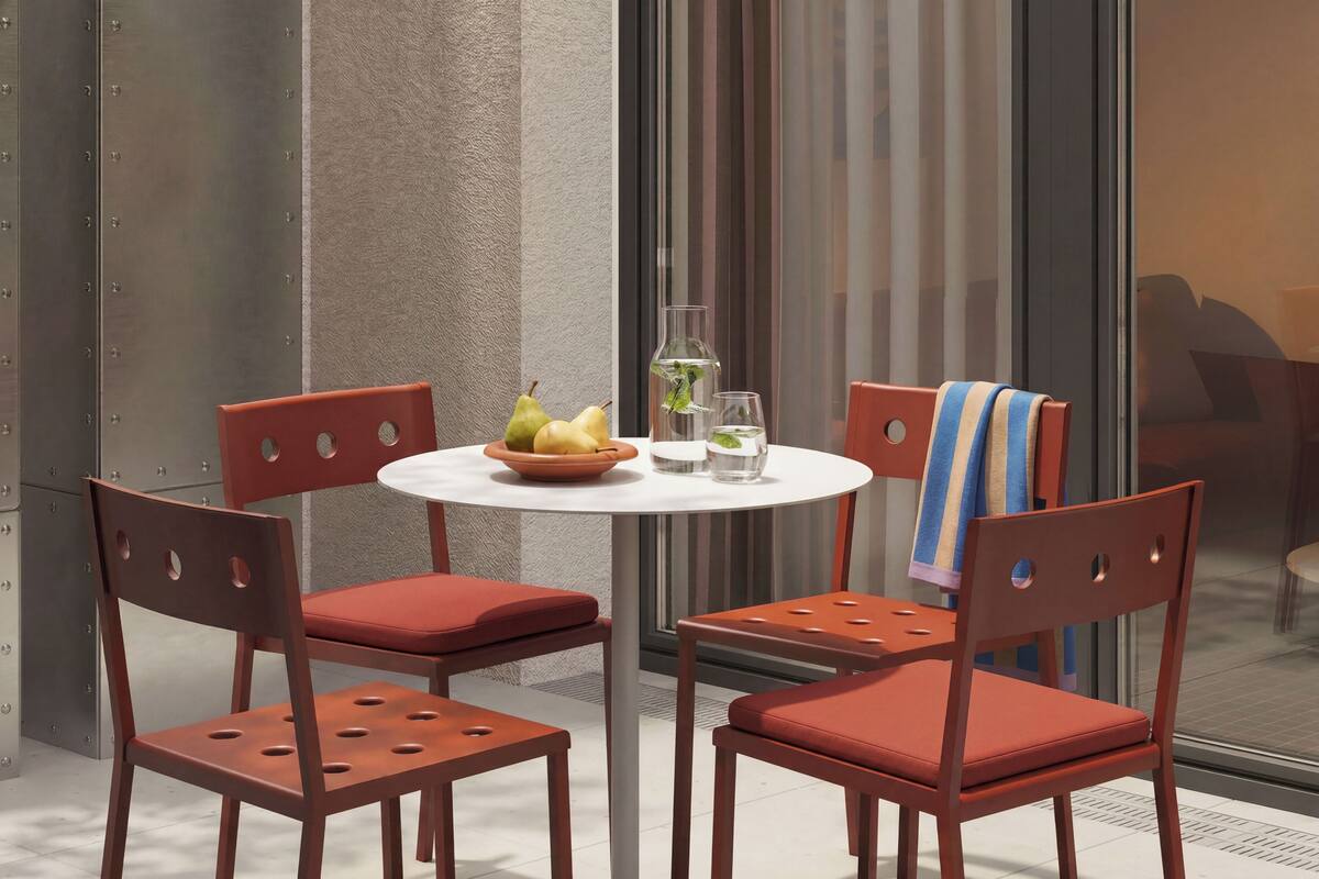 Ein Tisch mit Stühlen, eine Obstschale und Gläsern auf einer Terrasse.