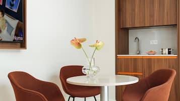 A modern kitchen with wooden cabinets, a white countertop, and a round dining table with two brown chairs.