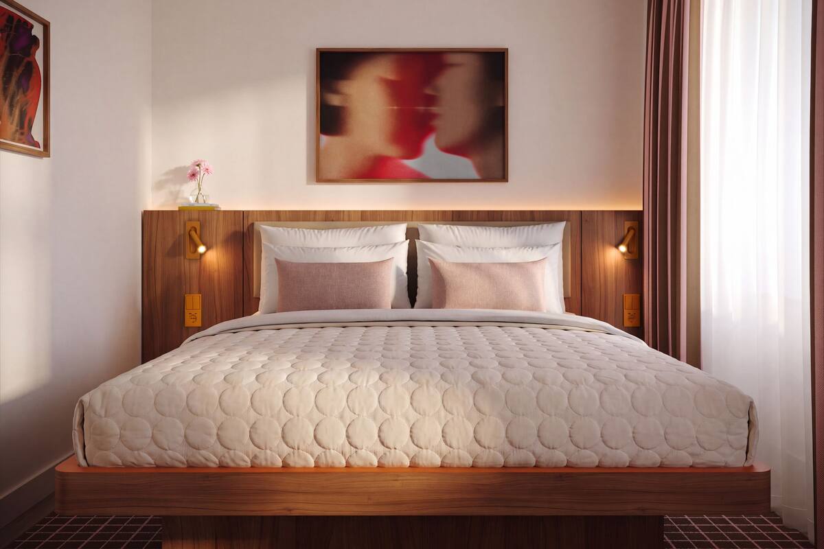 Ein Schlafzimmer mit einem Holzkopfende, zwei Kissen, einer gesteppten Bettdecke und einem Bild an der Wand.