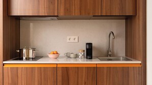 Una cocina con armarios de madera, un lavamanos de acero inoxidable, una tetera y una cafetera.