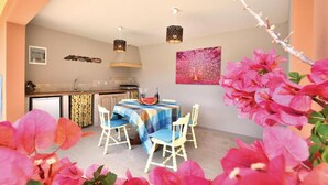 Zona pranzo con tavolo apparecchiato per quattro, cucina sullo sfondo e un elemento decorativo a parete.
