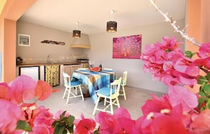 A dining area with a table set for four, a kitchen in the background, and a decorative wall piece.