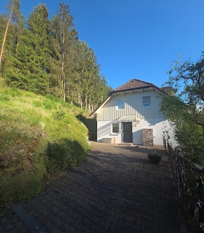Uma casa com calçada pavimentada, porta da frente e varanda pequena.