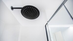 Un pommeau de douche au design circulaire, doté d’une poignée.