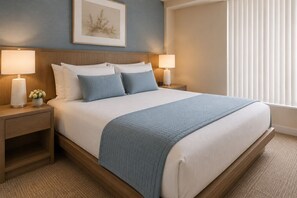 A hotel room with a bed, two bedside lamps, a nightstand, a framed picture on the wall, and a window with blinds. - The Aeris Suites (Toronto)