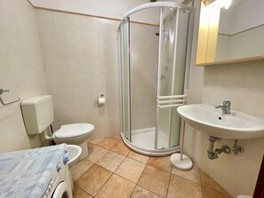 Een badkamer met toilet, douche, wastafel en een handdoekrek.