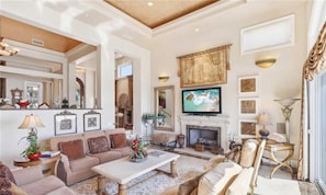 A spacious living room with a fireplace, comfortable seating, and a television.
