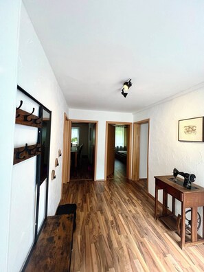 A hallway with wooden flooring, a sewing machine on a table, and a wall-mounted light fixture.