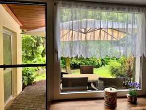 A room with a sliding glass door leading to a patio with wicker furniture and a table.