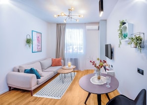 A modern living room with a sofa, coffee table, and a TV. - HB apartments Politkovskaia (Tbilisi)