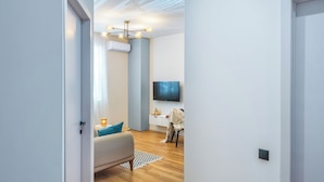 A modern living room with a sofa, a TV, and a ceiling light fixture. - HB apartments Politkovskaia (Tbilisi)