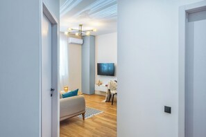 A modern living room with a sofa, a TV, and a ceiling light fixture. - HB apartments Politkovskaia (Tbilisi)