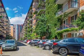 A row of parked cars along a paved street in a residential area with multi-story buildings, some with balconies and greenery. - HB apartments Politkovskaia (Tbilisi)