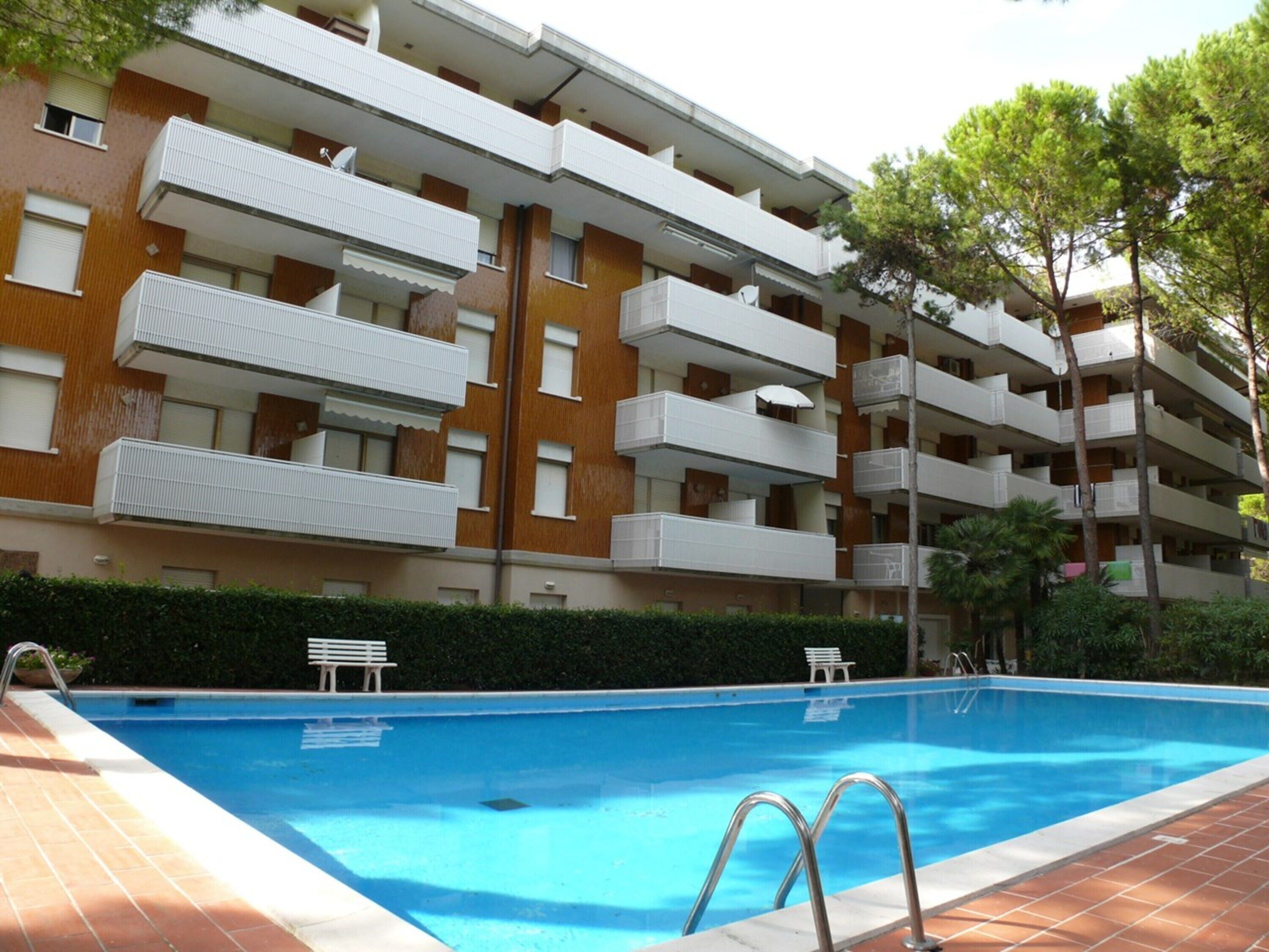 A multi-story residential building with balconies, a swimming pool, and a small garden area.