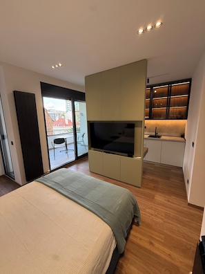 A modern bedroom with a large bed, a TV, and a sliding door leading to a balcony. - Tulum Apart Belgrade 2 (Beograd)