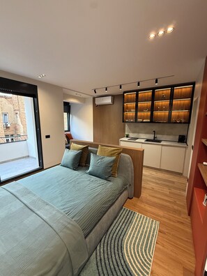 A modern bedroom with a large bed, a built-in desk, and a kitchen area. - Tulum Apart Belgrade 2 (Beograd)