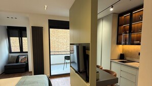 Une chambre moderne avec un lit, un bureau et une télévision. Elle dispose d’un balcon avec vue.
