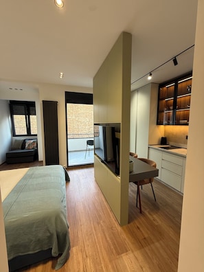Quarto moderno com cama, escrivaninha e televisão. Possui varanda com vista.